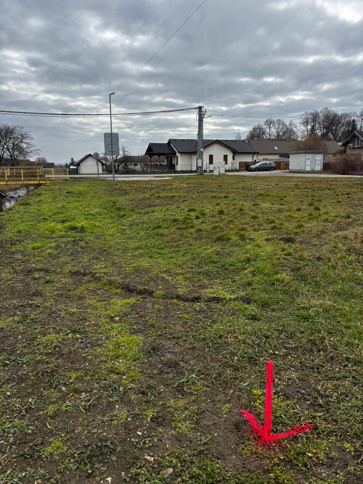 PRED — pohľad cez pozemok smerom k susednej rodinnej zástavbe a obecnej infraštruktúre.