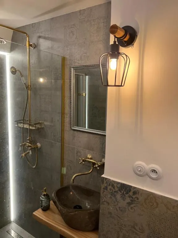 Kúpeľňa — prírodný kameň, mosadzné batérie, sivá obkladačka s ornamentom — remeselné prevedenie.