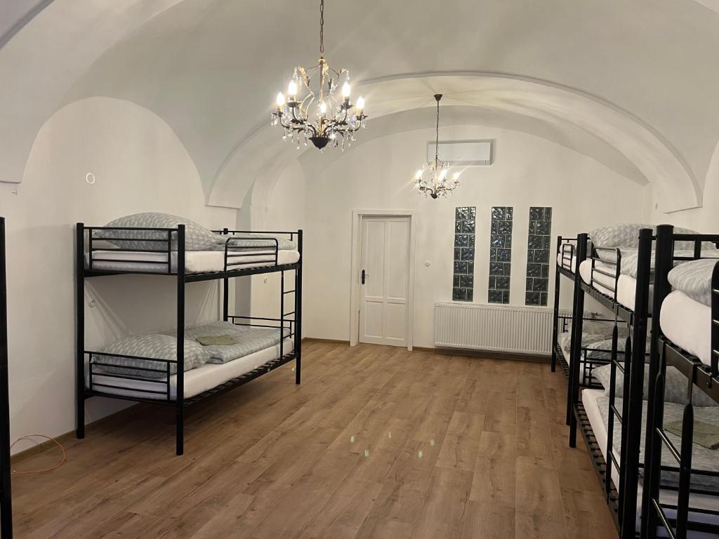 Menší dorm s klenbou, lustrom a presvetlením cez sklobetón — kombinácia historických detailov a moderného komfortu.