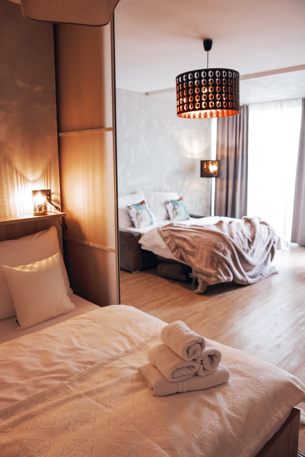 Ukážka typového apartmánu — spálňová časť, posedenie a vlastná kúpeľňa, vybavenie zodpovedajúce wellness pobytom.