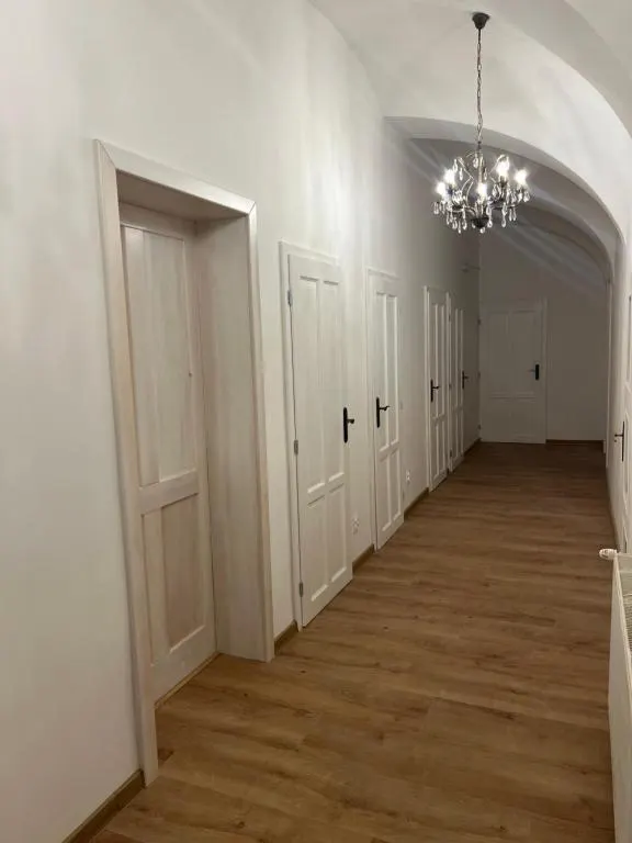 Centrálna chodba s klenutým stropom a dobovými dverami — citlivá obnova historickej dispozície.